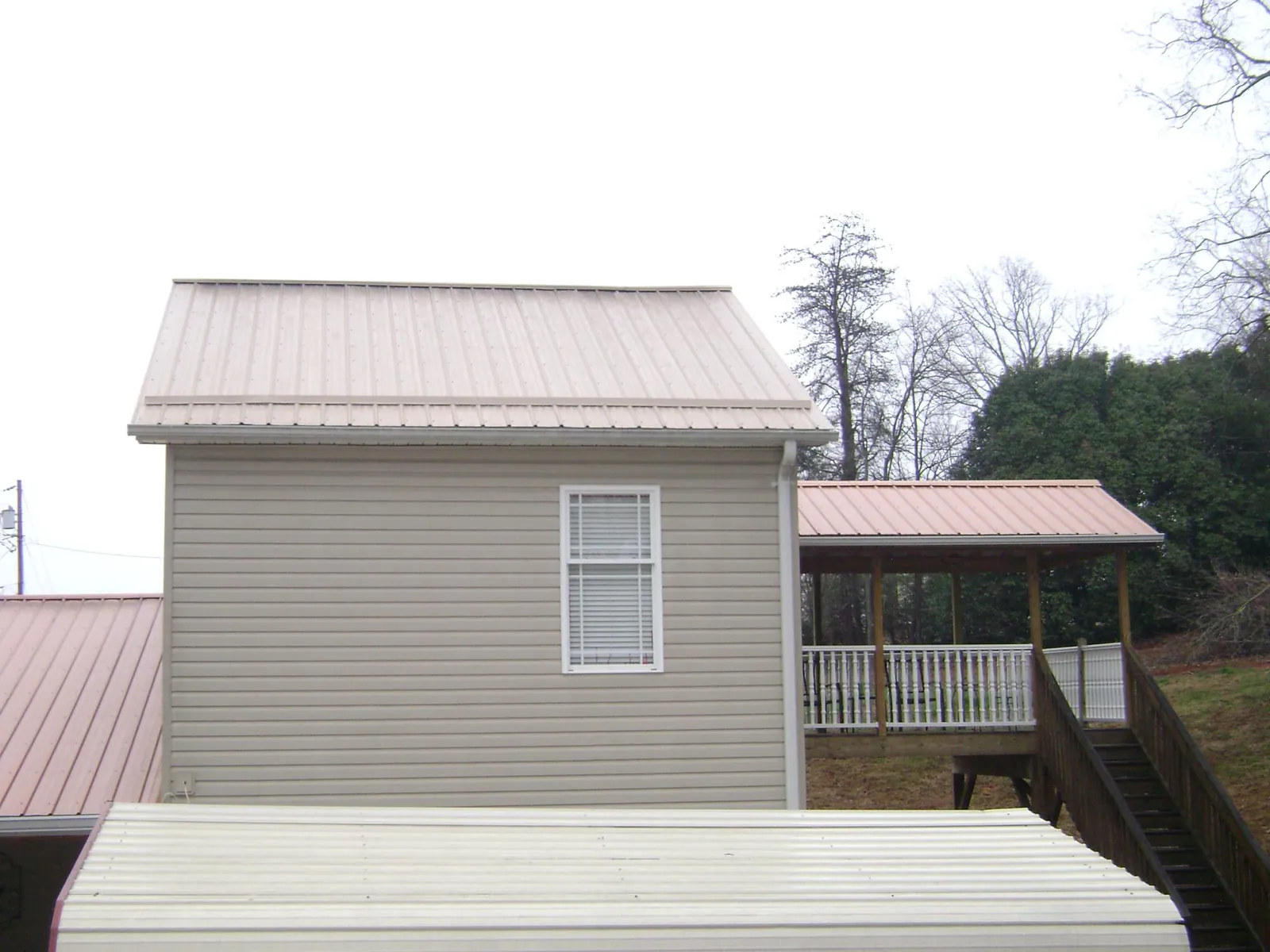 Tan metal roofs on a two story addition and attached porch, from a Roof Replacement job in Windham